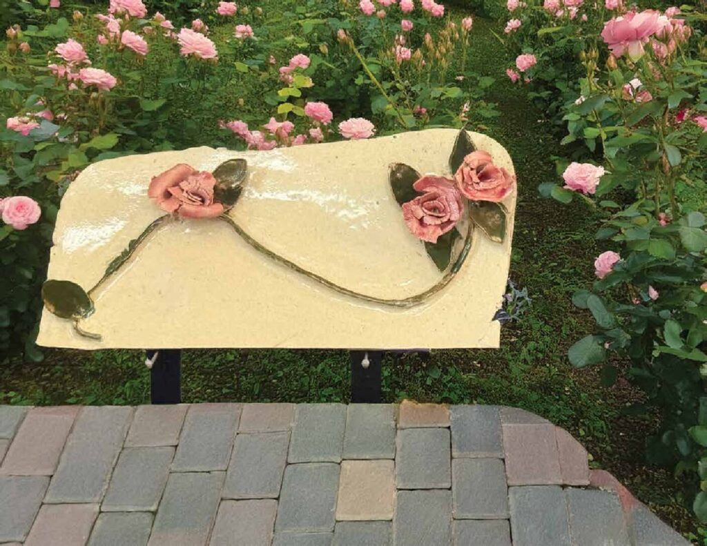 Cream clay wall hanging with sculpted pink roses along a curving vine