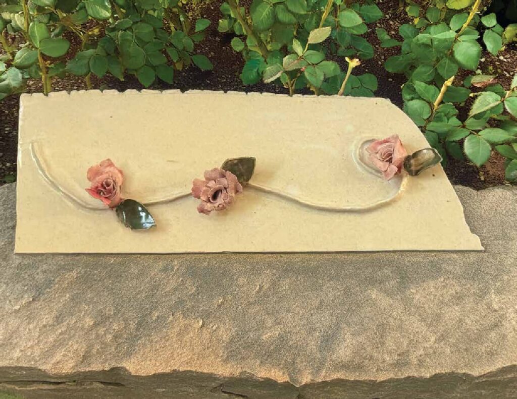 Cream clay wall hanging with three sculpted pink roses on a slender vine