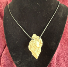Black cord necklace featuring a white shell pendant, resting on a textured purple towel. Ideal for showcasing beach-themed fashion accessories.