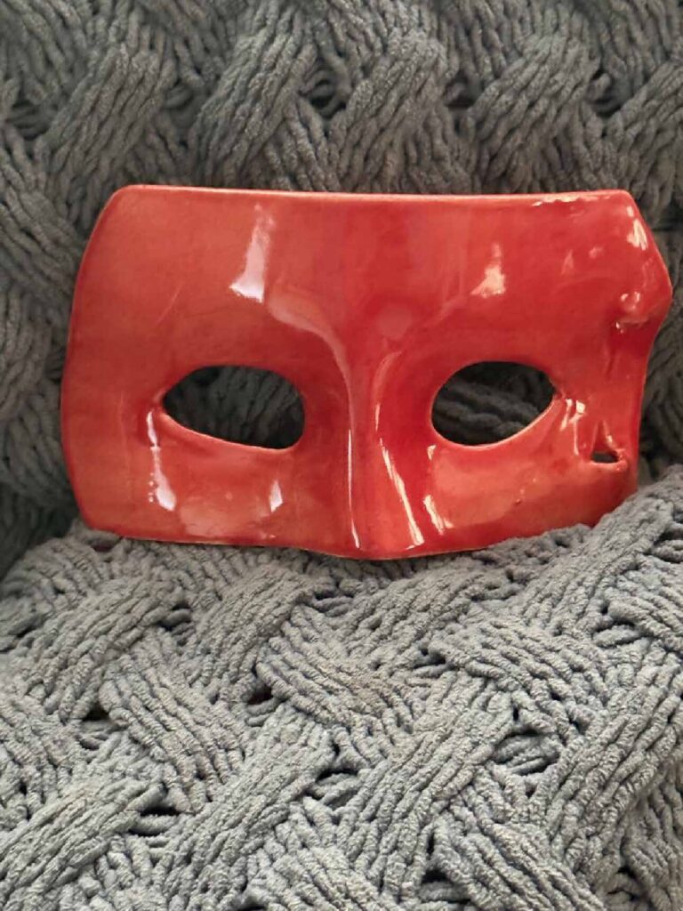 Handmade red clay masquerade mask with a retractable handle