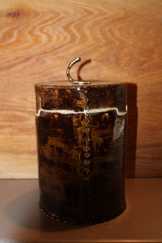 Round handmade ceramic canister with side handles in a brown glaze with a cream band