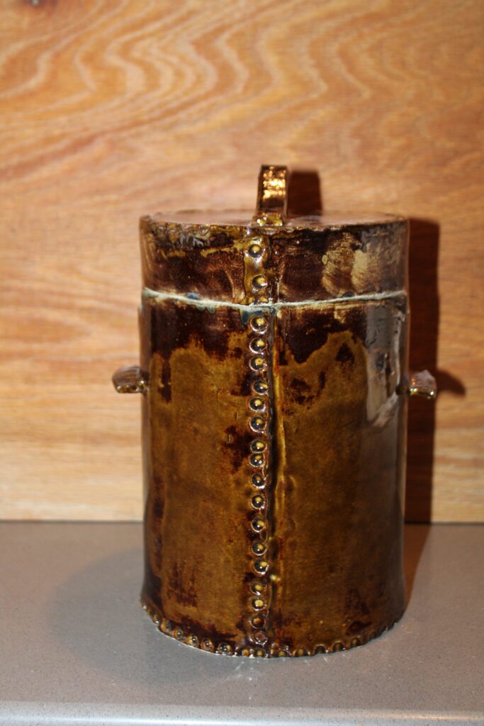 Round handmade ceramic canister with side handles in a golden amber glaze
